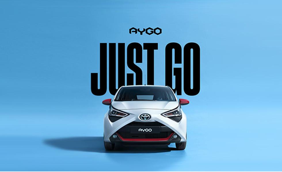 Weißer Toyota Aygo vor blauem Hintergrund